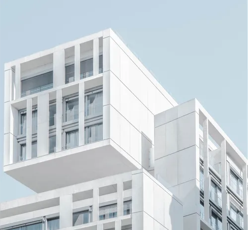 Modern white building with geometric architecture and large windows.