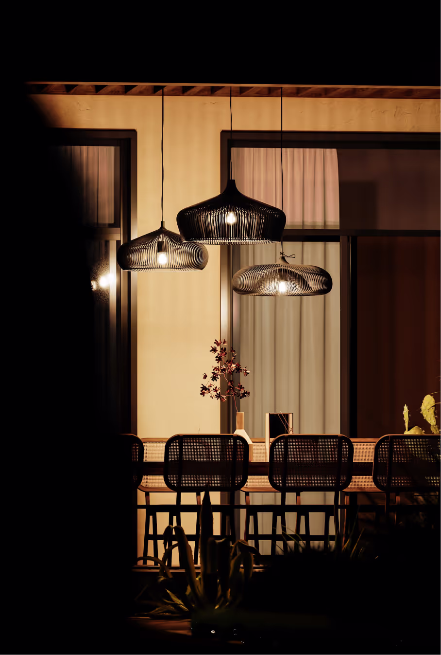 Cozy dining area with warm lighting, wicker chairs, and decorative pendant lamps.